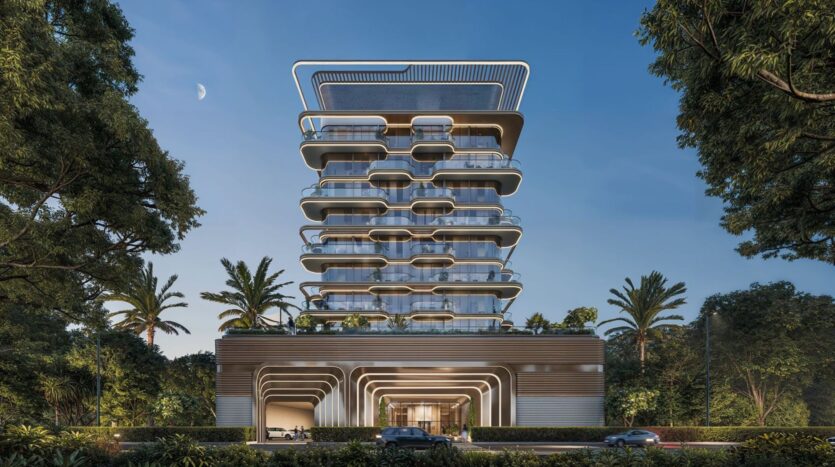 A modern multi-story building with curved balconies and large floor-to-ceiling windows, The Tides by Amis is surrounded by palm trees and lush greenery, with a few cars passing by on the road in front and a crescent moon in the sky.