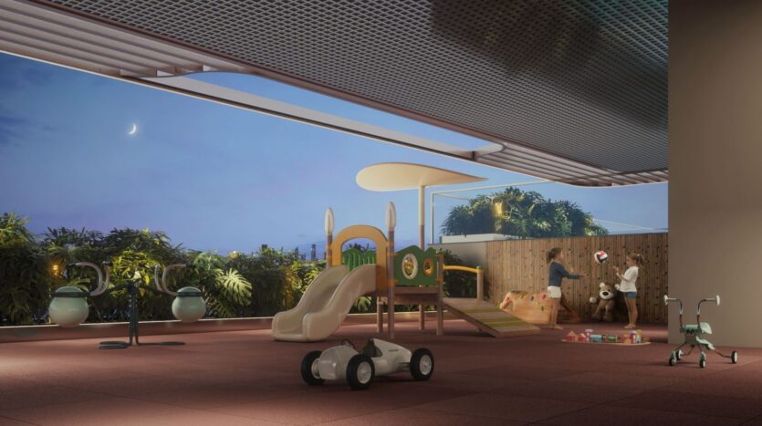 At dusk, a modern, covered outdoor playground—The Tides by Amis—features a slide, a small car, and ride-on toys. Two children are playing near a climbing structure and toy blocks, while green plants and trees line the perimeter beneath a crescent moon.