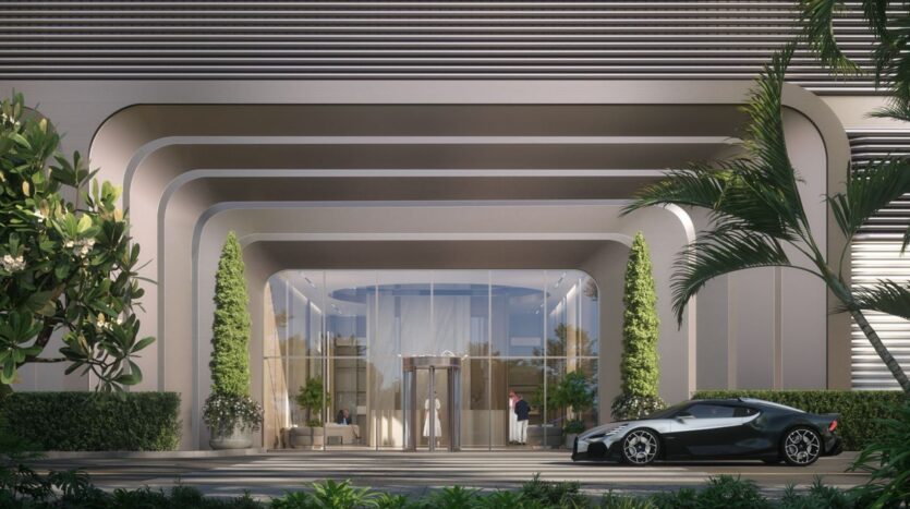 The entrance to the modern building of The Tides by Amis features curved architectural lines, large glass doors, tall green plants, and an elegant black sports car parked out front, all surrounded by lush greenery.