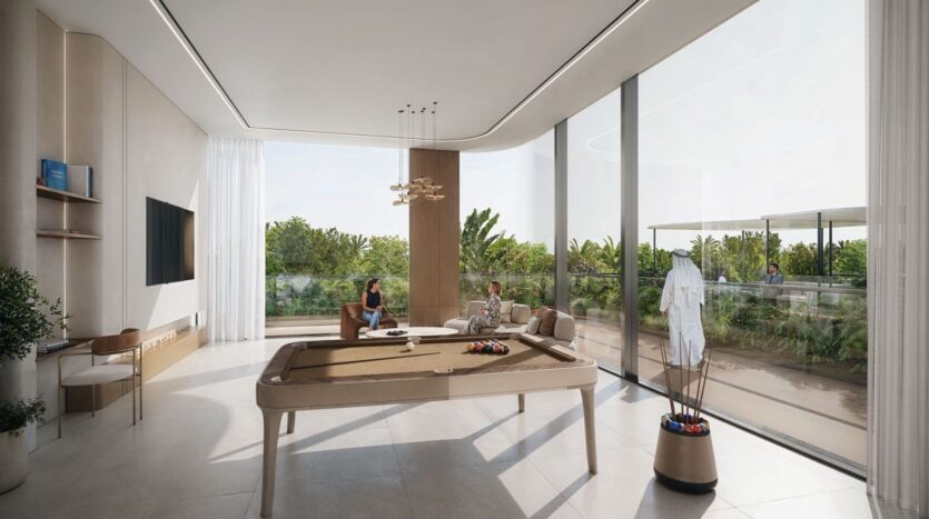 A modern, bright room with large windows, a pool table, and glass doors opening onto a lush garden. Two people are sitting at a table by the window, discussing *The Tides* by Amis. Natural light fills the space, creating an airy and relaxed atmosphere.