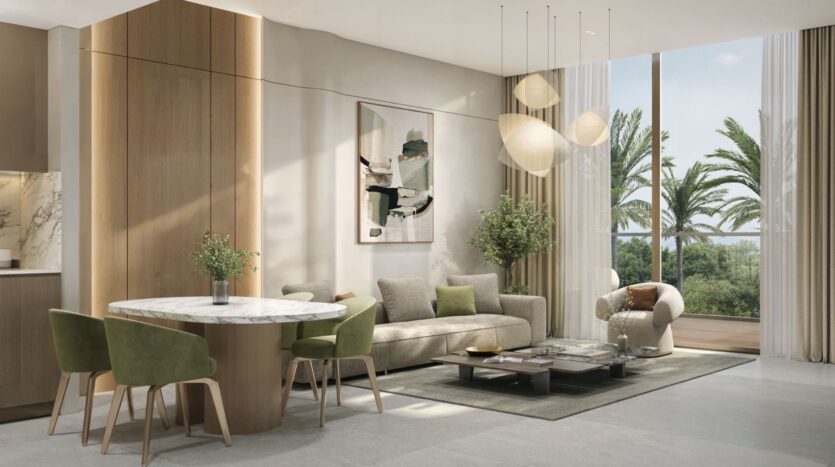 A modern living room featuring a round marble table, green chairs, a beige sofa, and abstract wall art. The Amis Tides collection inspires the decor, with pendant lights and large windows offering a view of the palm trees outside.