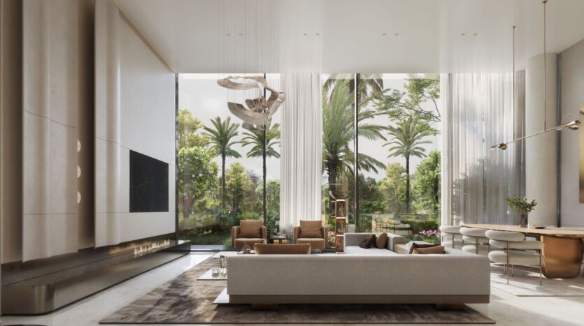 The modern, spacious lounge at The Tides by Amis features floor-to-ceiling windows overlooking lush palm trees. Neutral-toned furniture, a large beige sofa, elegant lighting fixtures, and a dining area create a luxurious and airy atmosphere.