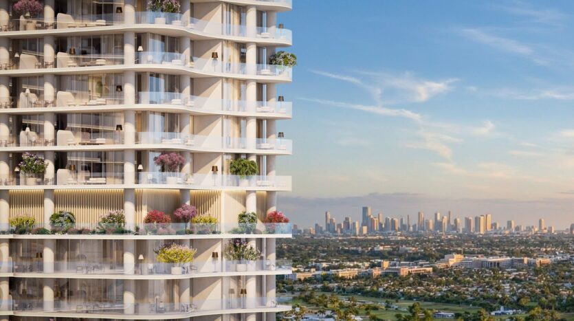 La Wow Tower, une tour moderne aux balcons ornés de plantes luxuriantes, surplombe un paysage urbain et une ligne d'horizon lointaine sous un ciel bleu parsemé de nuages épars.