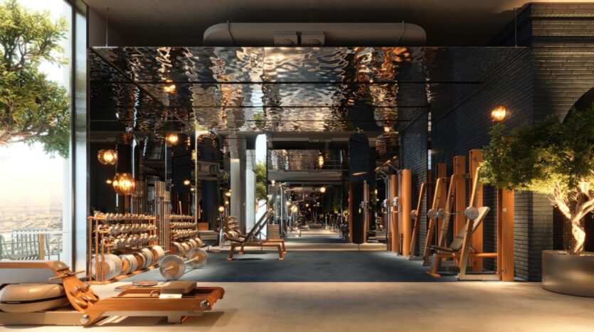 La salle de sport moderne et spacieuse de la tour Wow est équipée d'appareils de fitness en bois, de poids libres, de bancs et de fenêtres allant du sol au plafond, qui inondent l'intérieur épuré de lumière naturelle. Des plantes vertes ajoutent une touche de fraîcheur à cet espace élégant.