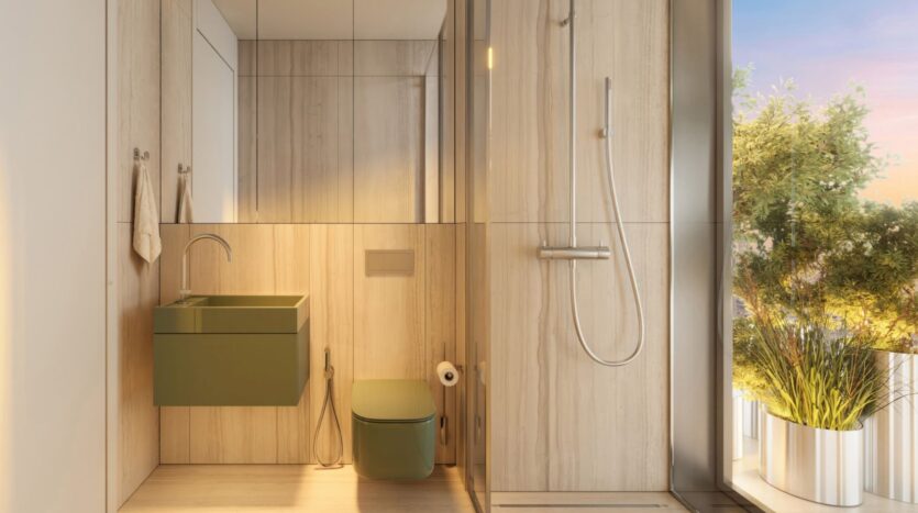 Salle de bains moderne avec des murs en bois clair à l'intérieur de la Tour Wow, un lavabo flottant vert et des toilettes assorties, une douche en verre à l'italienne, et de grandes plantes à côté d'une fenêtre laissant entrer la lumière naturelle du soleil.