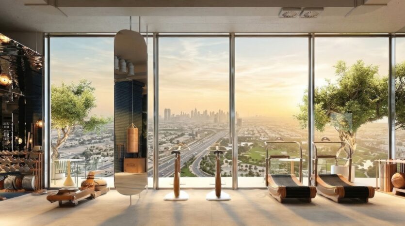 Salle de sport moderne et lumineuse à la Wow Tower avec des équipements d'exercice, de grandes fenêtres du sol au plafond, des arbres en pot, des accents en bois et une vue panoramique de la ville au lever ou au coucher du soleil.