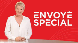 Una mujer de pelo rubio corto, vestida con una blusa blanca, sonríe ante un fondo rojo en el que se leen, en letras blancas y en negrita, las palabras «ENVOYÉ SPÉCIAL», lo que recuerda la decoración moderna de una inmobiliaria de Dubái.