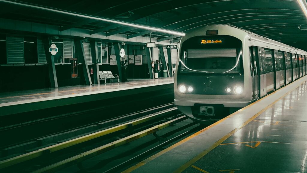 Un moderno treno della Gold Line entra in una stazione della metropolitana di Dubai, vuota e ben illuminata, con file di sedili e una chiara segnaletica sui binari.