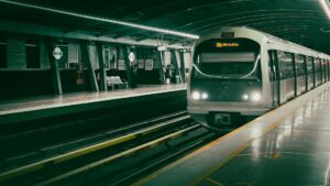 Un moderno tren de la línea Gold Line llega a una estación de metro vacía y bien iluminada de Dubái, con filas de asientos y una clara señalización de los andenes.