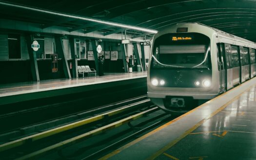 Un moderno tren de la línea Gold Line llega a una estación de metro vacía y bien iluminada de Dubái, con filas de asientos y una clara señalización de los andenes.