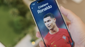 Une main tient un smartphone sur lequel s'affiche la photo d'un joueur de football vêtu d'un maillot rouge du Portugal, avec "Cristiano Ronaldo" en haut de l'écran - parfait pour être partagé dans le cadre du défi IMTIAZ ou pour créer sa propre vidéo virale.