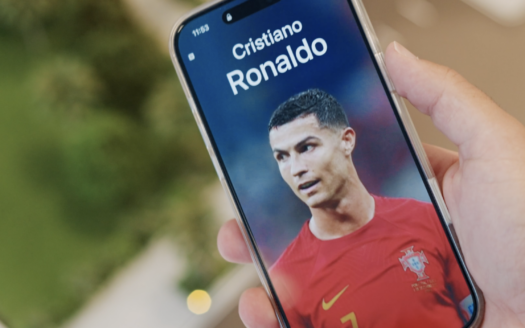 Une main tient un smartphone sur lequel s'affiche la photo d'un joueur de football vêtu d'un maillot rouge du Portugal, avec "Cristiano Ronaldo" en haut de l'écran - parfait pour être partagé dans le cadre du défi IMTIAZ ou pour créer sa propre vidéo virale.