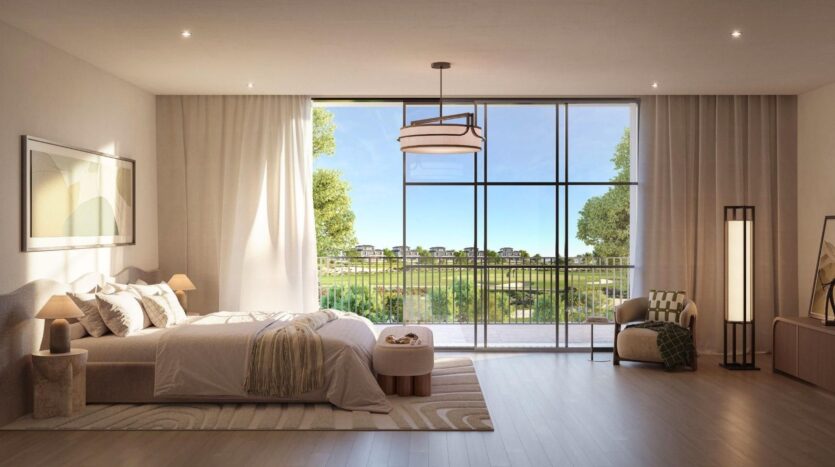 Une chambre moderne et spacieuse à Hudayriyat Golf Estates se caractérise par un grand lit, un décor neutre, des fenêtres allant du sol au plafond avec vue sur les paysages verdoyants et les maisons, un éclairage doux, un mobilier confortable et un design minimaliste.