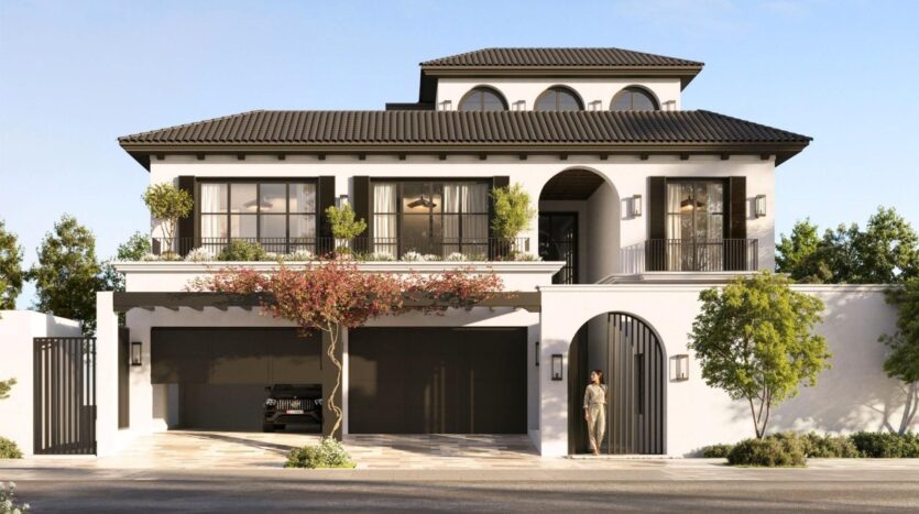 Maison moderne de deux étages à Hudayriyat Golf Estates avec des murs blancs, des garnitures noires, de grandes fenêtres, des balcons et des entrées voûtées. Une femme se tient près de l'entrée, une voiture est garée dans le garage et des arbres entourent la propriété.