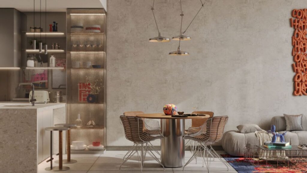 Une salle à manger moderne avec une table ronde, quatre chaises en fil de fer, des lampes suspendues et une cuisine attenante. Inspiré par Raw District d'Imtiaz, il comprend un présentoir à étagères en verre, un canapé en peluche et un art mural abstrait orange sur un mur beige texturé.