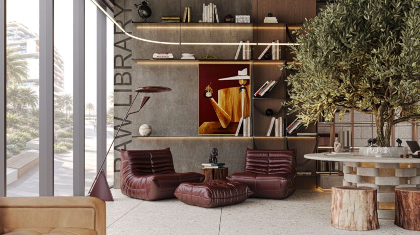 Une bibliothèque moderne avec de hautes étagères, des livres et des œuvres d'art inspirées de Raw District by Imtiaz. Deux chaises longues en cuir marron sont installées sous un tableau. Une table ronde, un arbre et des tabourets en bois sont placés devant de grandes fenêtres donnant sur des palmiers éclairés par le soleil.