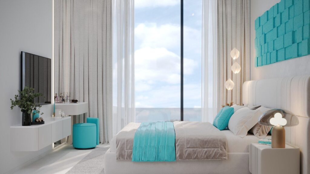 Une chambre à coucher moderne et lumineuse avec de grandes fenêtres, des murs blancs et une décoration minimaliste. Des coussins turquoise Reef 996 et un jeté égayent le lit, tandis que des accessoires assortis tels qu'un tabouret et des œuvres d'art murales complètent l'ensemble. La lumière naturelle remplit la pièce.
