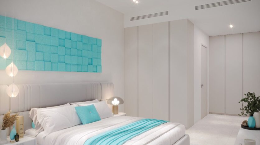 Une chambre à coucher moderne avec un lit blanc, des accents sarcelle dans le Reef 996, un art mural au-dessus de la tête de lit, une petite lampe de chevet, des armoires encastrées et une plante en pot dans le coin. La pièce est lumineuse et le décor minimaliste.