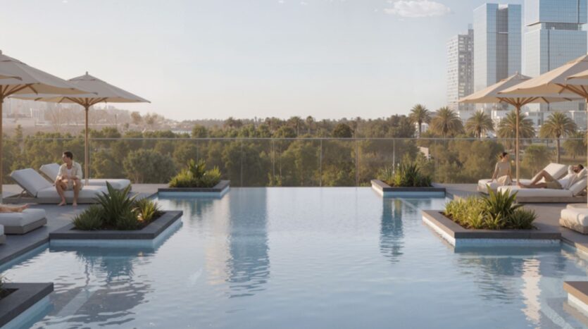 Une piscine à débordement avec des personnes se relaxant sur des chaises longues sous des parasols à Rotana Residences, entourée de verdure, avec de grands bâtiments modernes et des palmiers visibles à l'arrière-plan sous un ciel clair.