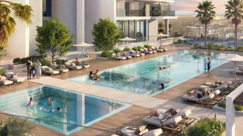 Piscine extérieure moderne des résidences Rotana avec deux bassins, des chaises longues, des gens qui nagent, prennent un bain de soleil et se détendent. Une végétation luxuriante, des palmiers et des vues lointaines sur l'océan ou la baie complètent cette oasis accueillante.