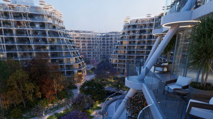 Des immeubles d'habitation modernes et incurvés, dotés de grands balcons, entourent Sakura Gardens, une cour paysagée remplie d'arbres, de plantes et d'allées. L'éclairage du soir crée une atmosphère paisible et accueillante.