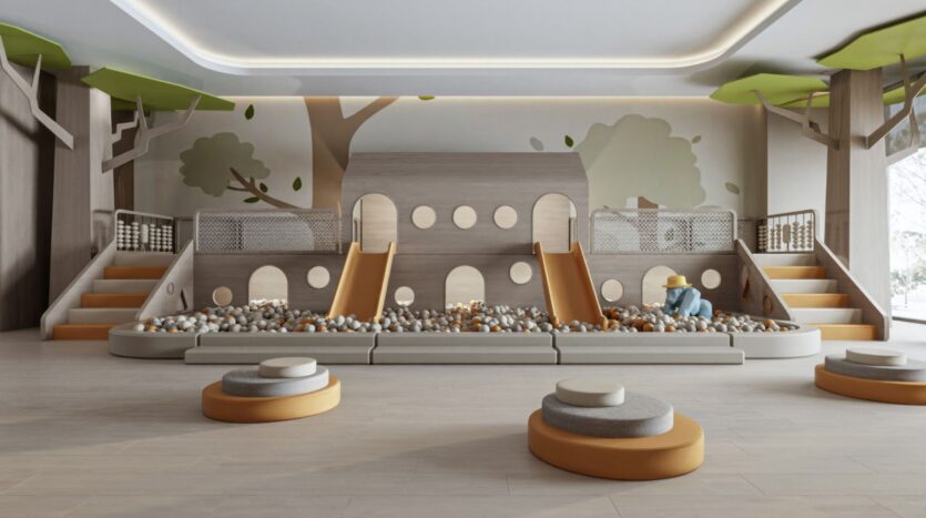 Une aire de jeux intérieure moderne avec une structure de jeux sur le thème de la cabane, deux toboggans orange et une fosse à balles remplie de balles de couleur neutre. Des sièges ronds rembourrés et des illustrations d'arbres sur les murs évoquent les jardins de Sakura, créant un espace ludique inspiré par la nature.