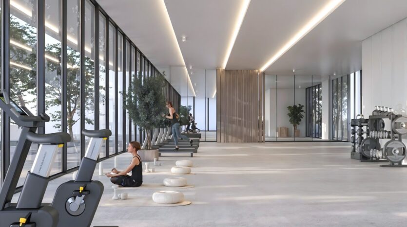Salle de sport moderne et spacieuse avec de grandes fenêtres dans les jardins de Sakura. On y trouve des vélos d'exercice, des poids libres, des tapis de yoga avec des coussins, et des gens qui s'entraînent ou méditent. La lumière naturelle remplit l'espace minimaliste et aéré, avec de la verdure visible à l'extérieur.