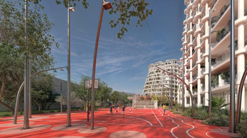 Un terrain de basket moderne en plein air avec des lignes courbes rouges et blanches se trouve près des jardins Sakura, entouré de grands immeubles d'habitation au design unique et d'arbres. Plusieurs personnes jouent au basket sous un ciel clair et lumineux.