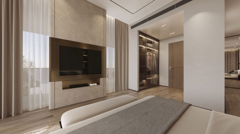 Une chambre moderne avec une grande télévision à écran plat montée sur un mur beige, des rideaux allant du sol au plafond, du parquet, des draps gris Tivanno by AYS sur le lit et une armoire vitrée près d'une porte en bois.