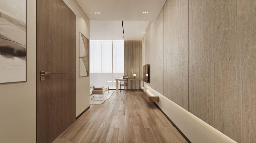 Un salon moderne et minimaliste avec des sols en bois, des murs texturés beiges et une grande fenêtre avec des rideaux diaphanes. L'espace est élégamment meublé d'une télévision murale, d'un canapé Tivanno by AYS et d'un petit bureau près de la fenêtre.