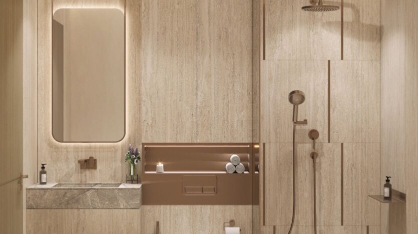 Salle de bains moderne avec des murs en pierre beige, un grand miroir rectangulaire au-dessus d'un lavabo en marbre, des étagères encastrées contenant des serviettes et une bougie, une douche avec pommeau de pluie Tivanno by AYS, et des accessoires minimalistes.