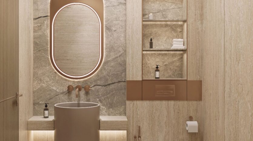 Salle de bains moderne avec des murs en marbre beige, un lavabo rond, un miroir ovale rétroéclairé et des étagères ouvertes Tivanno by AYS contenant des serviettes et des bouteilles. Le robinet mural et le porte-papier hygiénique ajoutent à la chaleur, au minimalisme et à l'élégance du design.