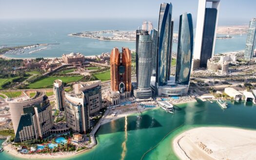 Vue aérienne de la ligne d'horizon d'Abu Dhabi avec ses gratte-ciel modernes, ses hôtels, sa plage, son eau turquoise et ses espaces verts - on peut apercevoir les avantages et inconvénients de l'immobilier à Abu Dhabi sur fond de golfe Persique qui s'étend au loin.