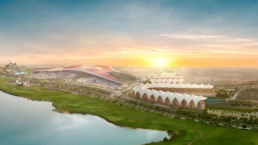 Vue aérienne de l'île de Yas à Abu Dhabi au lever du soleil, avec la structure à toit rouge de Ferrari World et les attractions voisines, mettant en évidence les avantages et inconvénients de l'immobilier à Abu Dhabi au milieu de la verdure, des parkings et des paysages de bord de mer.