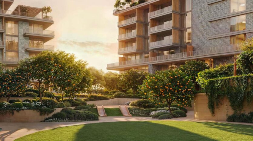 Des immeubles d'habitation modernes entourent une cour luxuriante à Arancia Yards by Beyond, avec des orangers, des buissons manucurés et une pelouse, le tout baigné par la lumière chaude du soleil.