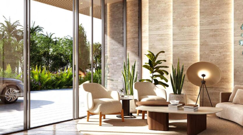 Hall d'entrée moderne à Arancia Yards by Beyond avec de grandes fenêtres, des fauteuils beiges, des tables en bois, des plantes d'intérieur et un lampadaire. La lumière du soleil pénètre à flots, mettant en valeur les murs texturés, la verdure et une voiture garée à l'extérieur.