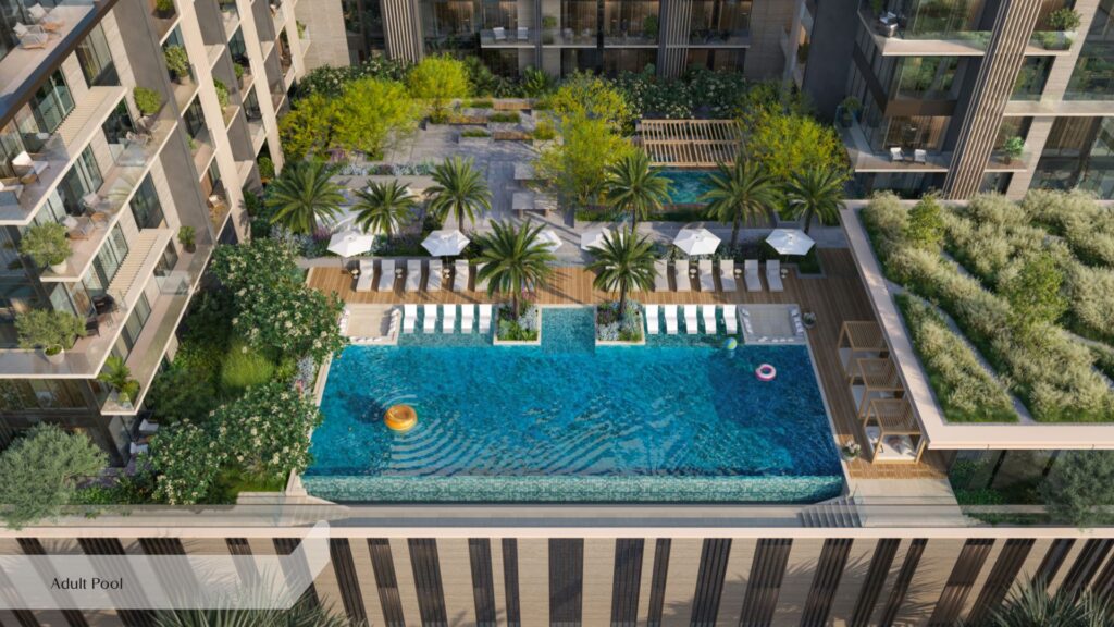 La piscine à débordement située sur le toit de l'Everly Place by Ellington est entourée de chaises longues, de palmiers et de coins salon ombragés, avec en toile de fond des immeubles d'appartements modernes et un aménagement paysager luxuriant. On aperçoit des bouées dans l'eau.