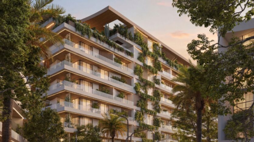 Lunaya Terraces est un immeuble d'appartements moderne à plusieurs étages, doté de grands balcons agrémentés de plantes vertes et d'arbres, niché au cœur d'un écrin de verdure, sous un ciel aux couleurs chaudes du coucher de soleil.