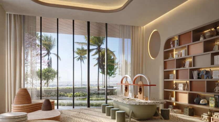 Une salle de jeux moderne au Mövenpick Residences, dotée d'une grande baie vitrée donnant sur des palmiers et de la verdure, avec des sièges bas, une table de jeux garnie de jouets, une bibliothèque encastrée contenant divers objets, et un éclairage naturel et tamisé.