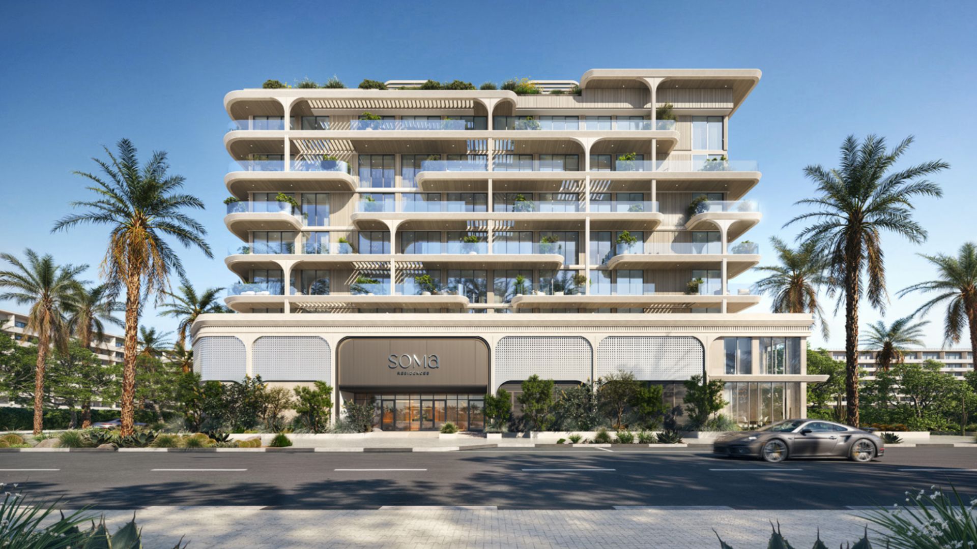 Un immeuble moderne de plusieurs étages, construit par Origami Developments, se distingue par ses grandes baies vitrées et ses balcons incurvés, au milieu d’une plantation de palmiers. Une voiture argentée passe dans la rue en face. L’enseigne de l’immeuble indique « SONA ».