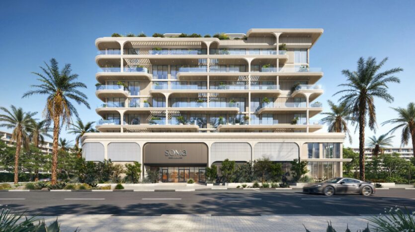 Immeuble moderne de plusieurs étages, doté de grandes baies vitrées, de balcons blancs et d'espaces verts à chaque étage, entouré de palmiers. Une voiture élégante passe devant l'entrée portant l'inscription « SONIA », qui fait partie de la collection haut de gamme Soma Residences.