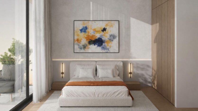 Une chambre à coucher moderne de Winslow avec un lit, une literie blanche, un jeté orange, un tableau abstrait au-dessus de la tête de lit, des lampes murales, une fenêtre allant du sol au plafond avec des rideaux transparents et des accessoires en bois élégants.