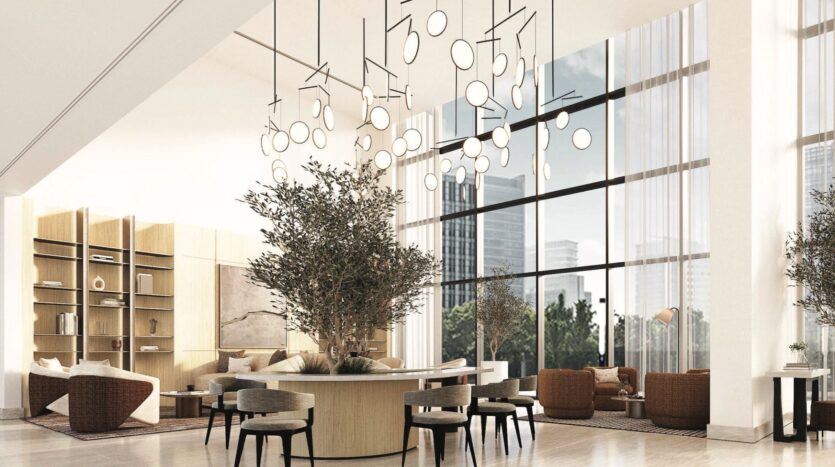 Salon spacieux et moderne de Vida Residences Saadiyat Island avec de grandes fenêtres, de grandes plantes d'intérieur, des luminaires circulaires contemporains et des meubles aux tons neutres. Des étagères en bois clair et des sièges créent une atmosphère accueillante avec vue sur le paysage urbain.