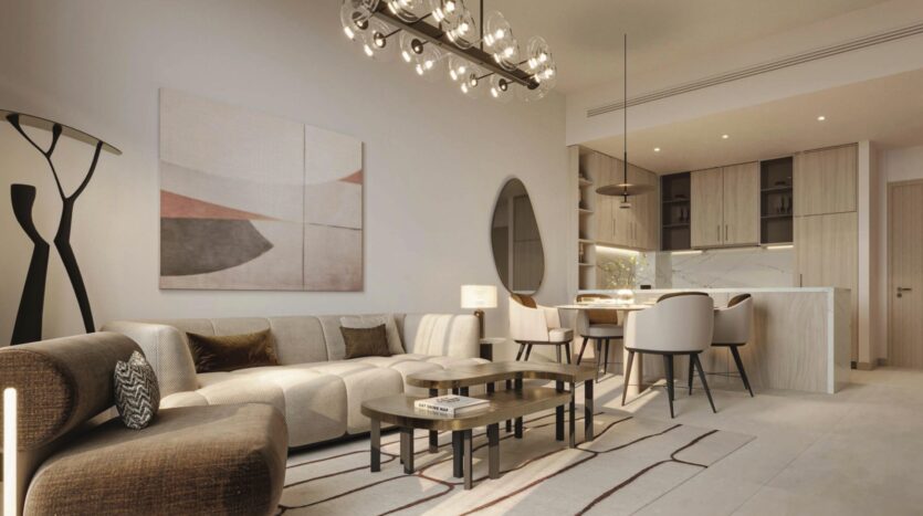 Un salon et une salle à manger modernes à Vida Residences Saadiyat Island avec des tons neutres, un canapé sectionnel, un art mural abstrait, une table à manger ronde et des chaises, un éclairage suspendu et une cuisine ouverte minimaliste à l'arrière-plan.