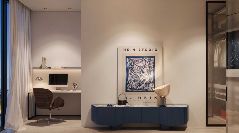 Une chambre moderne et minimaliste de la Villa Del Garda comprend un petit bureau et un ordinateur sur la gauche, une chaise brune et un buffet bleu avec des objets décoratifs sous un grand poster abstrait encadré sur un mur blanc. Un placard est partiellement visible sur la droite.