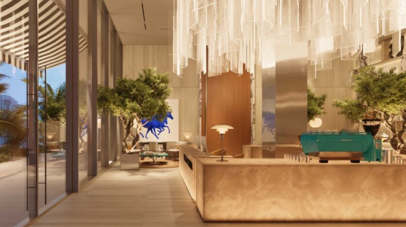 Un café moderne et élégant inspiré de la Villa Del Garda, avec des comptoirs en marbre, des arbres d'intérieur, une machine à expresso turquoise, des meubles élégants et une étonnante sculpture de cheval bleu. De grandes fenêtres et un lustre avec des lampes suspendues complètent l'ambiance.
