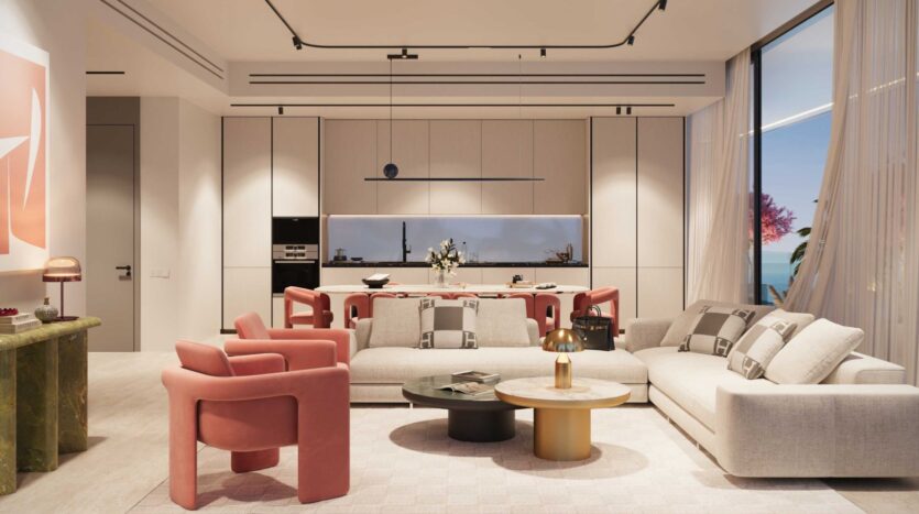 Le salon moderne de la Villa del Garda est composé de canapés beiges, de fauteuils rose corail, d'une table basse ronde et d'une cuisine en arrière-plan. De grandes fenêtres avec des rideaux diaphanes offrent une vue pittoresque sur l'océan à l'extérieur.