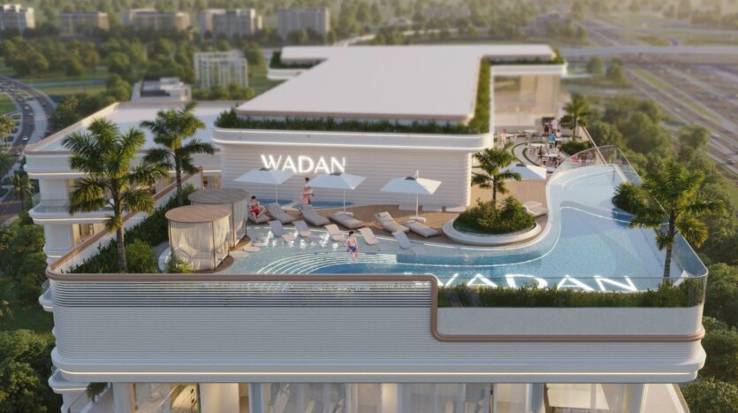 La piscine à débordement du Weston by Wadan est équipée de chaises longues, de parasols, de palmiers et de personnes en train de se détendre. Le bâtiment affiche "WADAN" en grosses lettres, avec en arrière-plan des routes urbaines et une végétation luxuriante.