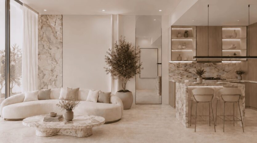 Le salon et la cuisine modernes du Beverly Crown, conçu par HMB, se distinguent par leurs plans de travail en marbre, un canapé aux lignes courbes, une table basse ronde en marbre, des étagères ouvertes, des tabourets de bar, des plantes en pot et de grandes baies vitrées laissant entrer la lumière naturelle.