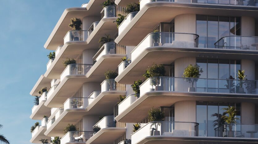 Immeuble d'appartements moderne aux balcons incurvés, aux balustrades en verre et aux plantes en pot. La façade blanche du Château Piétrus se détache avec élégance sur un ciel d'un bleu limpide.